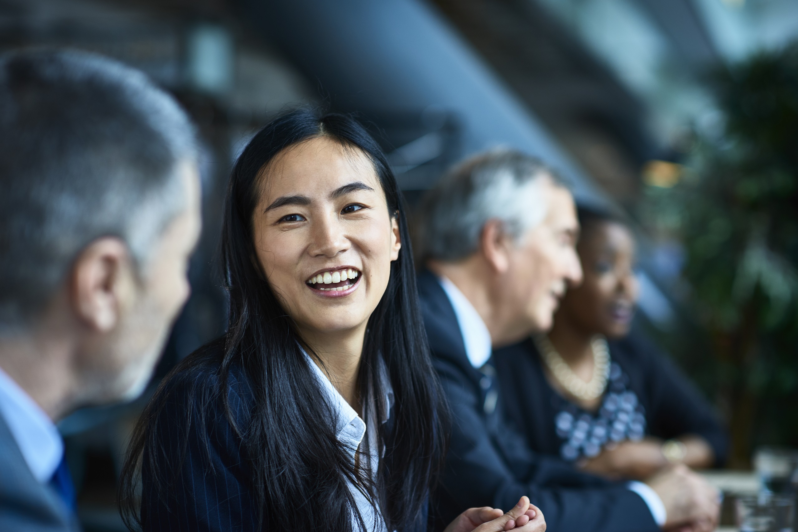 Close up portrait of Asian businesswoman, beside male senior coworker, smiling and laughing, respect, admiration